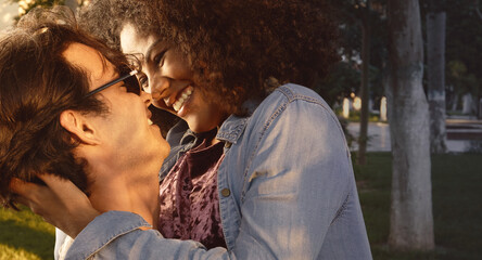  portrait of multiracial couple in love and happy embracing in the park