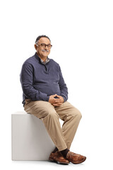 Mature casual man sitting on a white cube