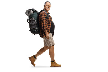 Full length profile shot of a mature hiker with a backpack walking and smiling
