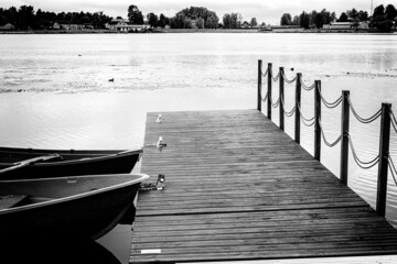 Two old rowing boats at jetty footbridge, monochrome black and white