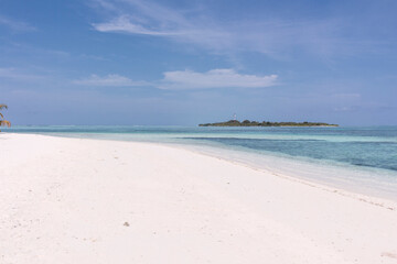 Playa paradisiaca soleada, agua cristalina y cielo azul, isla al fondo