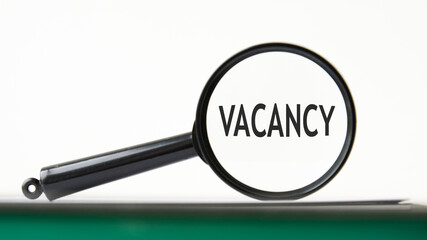 magnifying glass with text vacancy on notebook
