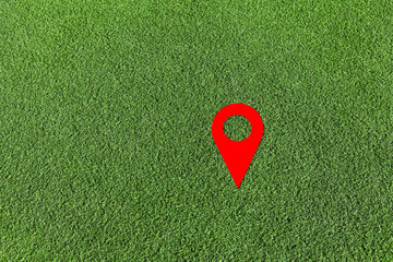Red geo locate symbol on green lawn. Design element. Artificial green grass. Empty space