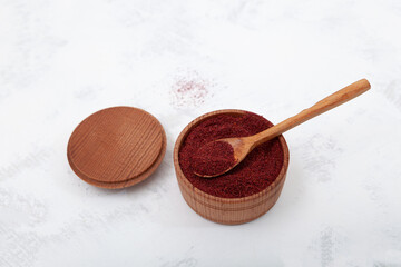 Dried ground red Sumac powder spices in wooden bowl. Sumac is spice used as a spice in Middle Eastern cuisine to add tart, lemony taste to salads or meat