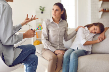 Female psychologist counseling parent. Serious single mom and sad unhappy child sitting on sofa and...