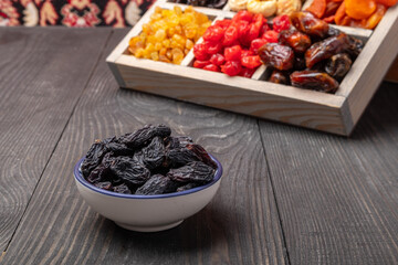 dark raisins in a bowl on a wooden background