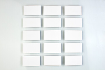 Mockup of horizontal business cards stacks arranged in rows at white textured paper background.