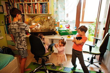 Fototapeta premium Four children holding their favorite pets on hands. Kids playing with hamster,turtle and parrots at home.