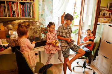 Four children holding their favorite pets on hands. Kids playing with hamster,turtle and parrots at home.