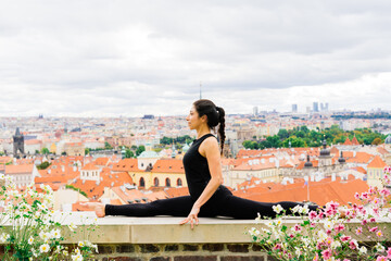 Fototapeta na wymiar Female does yoga in the background of the city of Prague