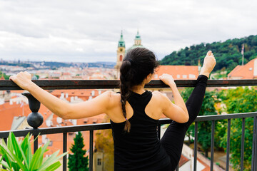 Female does yoga in the background of the city of Prague