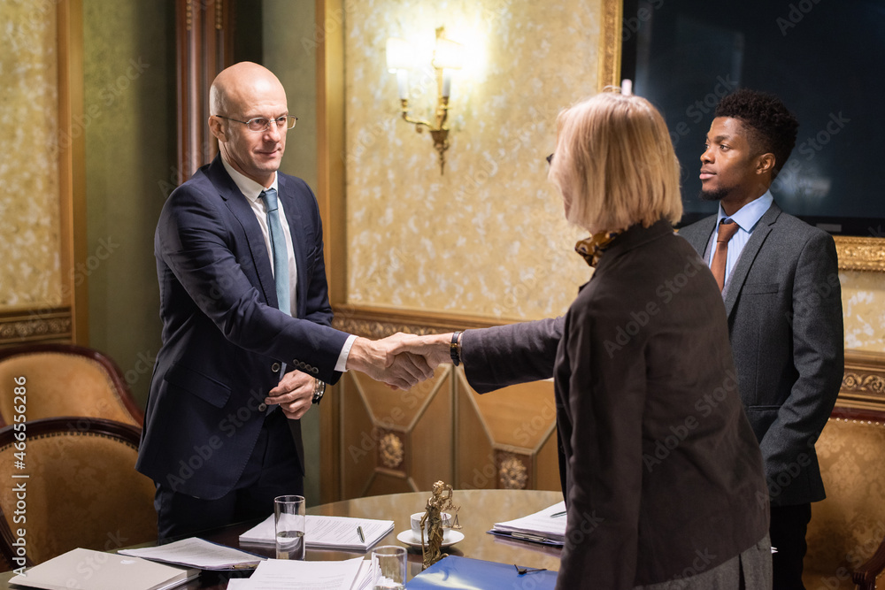 Aufkleber two mature business partners shaking hands over table with papers after signing all necessary docume