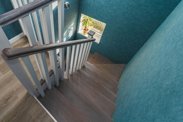 View of a wooden staircase with white railings and turquoise walls