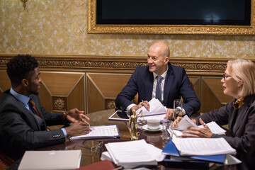 Group of intercultural lawyers gathered by table having discussion of main points of juridical...