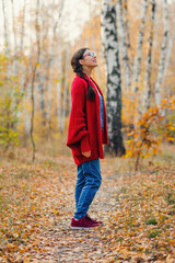 woman stands and admires the beauty of nature in the autumn forest