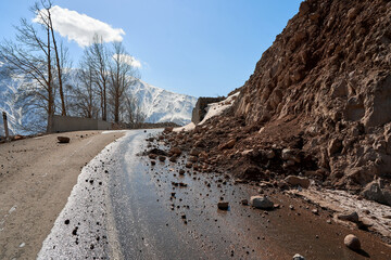 Early spring in the mountains. The rocks fell on the road. Dangerous bugle road. Rockfall in the mountains - obrazy, fototapety, plakaty