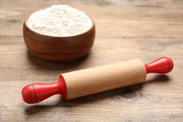 Fototapeta na wymiar Rolling pin and bowl with flour on wooden background