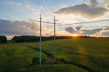 Fototapeta na wymiar High voltage tower with electric power lines between green agricultural fields. Transfer of electricity concept