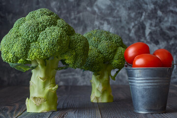 Two heads of broccoli sit on a dark wooden table,