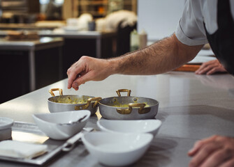 detail of a chef seasoning a freshly cooked dish, before serving at the table. concept of haute cuisine and gourmet food.