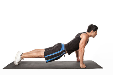 Portrait of strong handsome athletic man standing in plank position, working out on fitness mat, doing Phalakasana exercise on straight arms. Indoor studio shot isolated on white background.