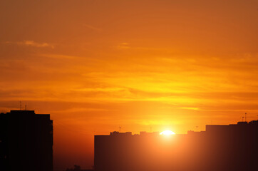 Fototapeta premium The setting sun over urban residential buildings.