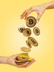 Woman's hand giving golden bitcoin to another hand on vibrant yellow background. Creative cryptocurrency or blockchain concept. Stock Market, digital gold money and stock investment business.