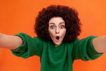 Portrait of shocked woman with Afro hairstyle wearing green casual style sweater standing with open...