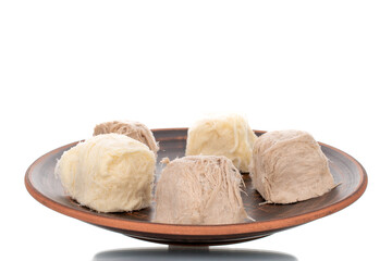 Several sweet cotton candy on a ceramic plate, close-up, isolated on white.