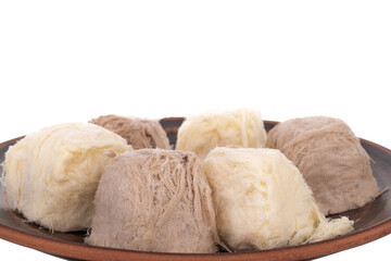 Several sweet cotton candy on a ceramic plate, close-up, isolated on white.