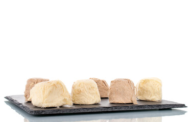 Several sweet cotton candy on a slate stone, close-up, isolated on white.