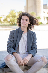 young long hair man sitting on the street