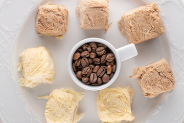 Several delicious cotton candy on a ceramic dish with a cup of coffee beans, close-up, top view.