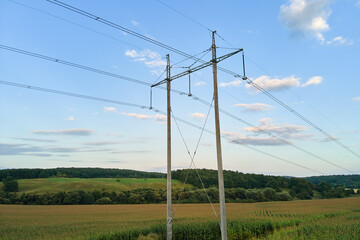 Tower with electric power lines for transfering high voltage electricity located in agricultural cornfield. Delivery of electrical energy concept.