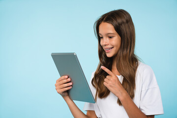 Happy caucasian young teenager girl schoolchild pupil student using digital tablet pointing at...