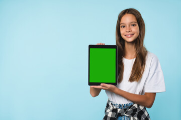 Cropped close up cutout portrait of smiling caucasian schoolgirl teenager child pupil student holding digital tablet showing blank screen with advert place mockup isolated in blue background