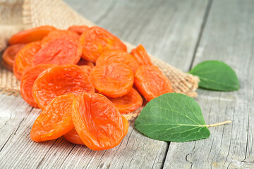 Dried apricots with green leaves on rustic wooden background