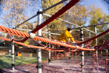 Children's recreation area in the park. Stretched ropes for climbing and climbing up. Sunny autumn weather
