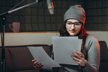 Woman preparing material before radio show, studio recording. Soundproof room for professional recording vocal. Voice artist works with material of some broadcast live show. Dubbing