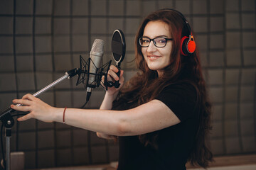 Female person records POP song at the recording studio. Singer emotionally gesturing with her...