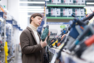 business man in a brown coat picking a screwdriver at a hardware store for repair