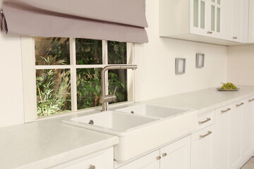 Fototapeta na wymiar White sink with tap near window in kitchen. Interior design