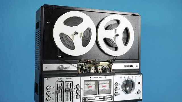 Rotating Old Reel-to-Reel Tape Recorder On A Blue Background.