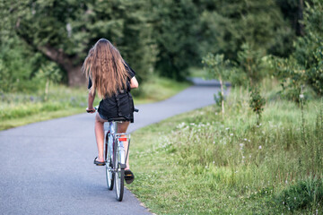 Obraz premium A young woman riding a bicycle in a park in summer.
