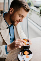 Young man drinking coffee in an outdoor cafe.