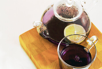 purple tea in a mug and teapot with lemon