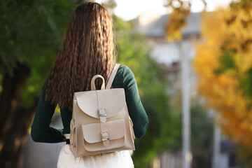 Fototapeta Young woman with stylish beige backpack in park, back view. Space for text obraz