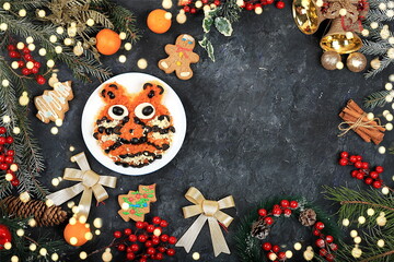 Christmas new year dishes, traditional festive tiger cub salad, symbol of the year made of carrots, olives, cheese for vegan food, fir branches and cones and decorations, food design idea,
