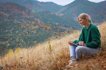 Naklejka na ściany i meble Young woman drawing on tablet in mountains, space for text