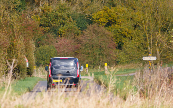 Black Ford Transit Custom Van Driving Through Scenic Autumnal Countryside